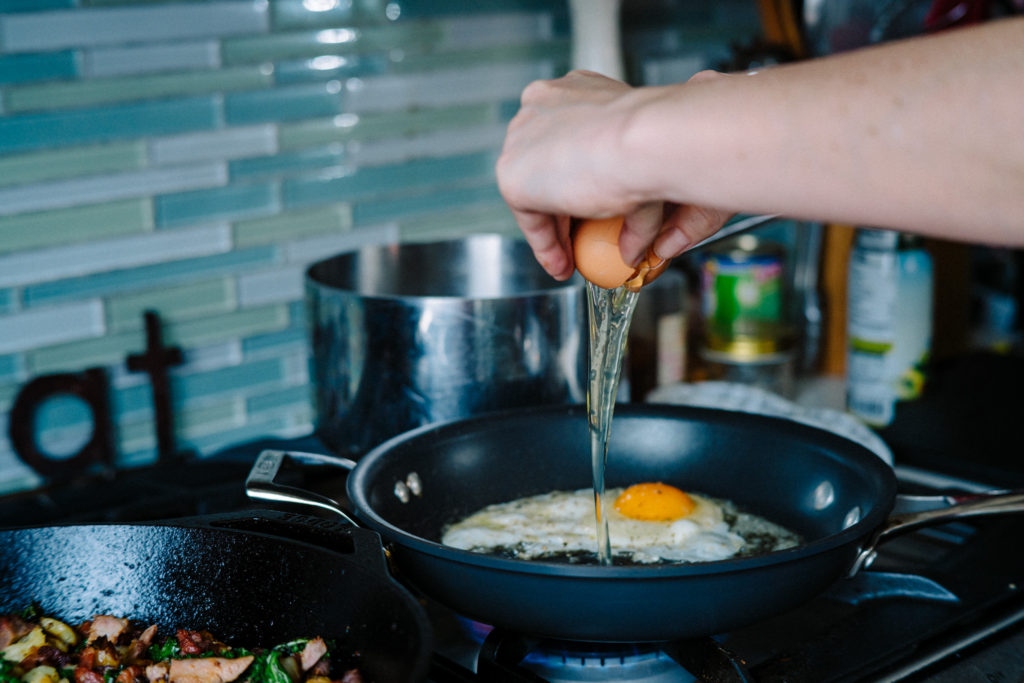 frying eggs in a nonstick skillet for breakfast hash
